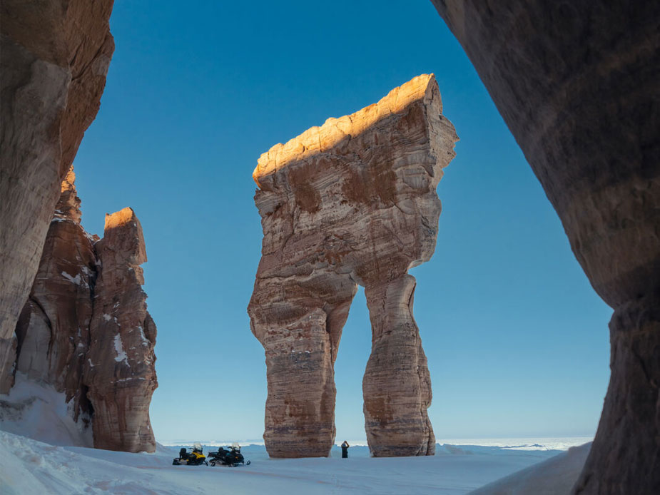 Une formation rocheuse massive, ressemblant à un pantalon, se dresse le long du rivage de l'océan dans l'Arctique.